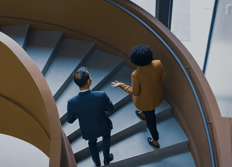 Two executives walking down a spiral staircase in conversation